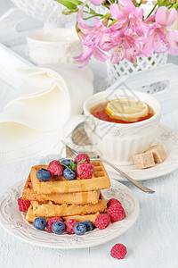 带甜华芙饼浆果和柠檬茶的大陆早餐图片