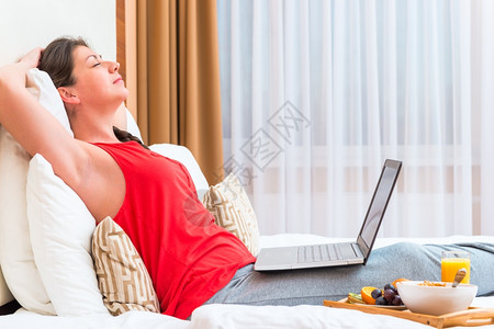 早餐酒店睡着的年轻女士膝上有电脑的年轻女士背景