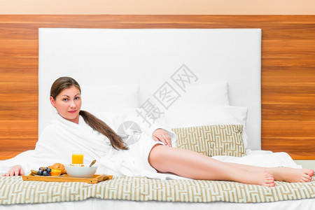 穿着浴袍的女睡衣床和早餐放在上图片