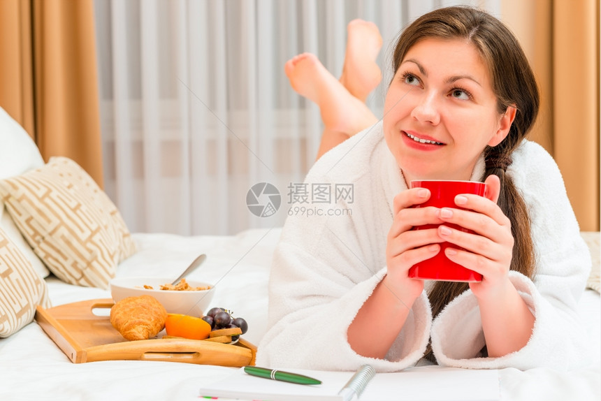 女人趴在床上喝咖啡吃早餐图片