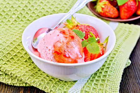白碗中的草莓糖浆和木板上餐巾纸的勺子草莓冰淇淋图片