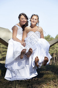 两个新娘在吊床上赤脚面对蓝天和森林背景图片
