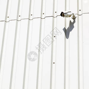 白色工业金属建筑墙壁上的监视摄像机图片