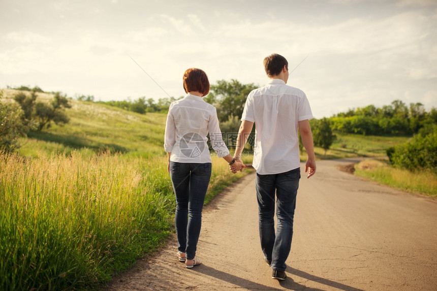 快乐的情侣在草坪旁牵手散步图片