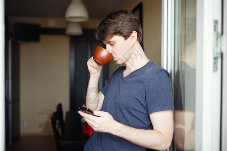 男人喝咖啡和使用移动智能手机图片