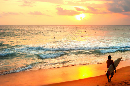 日落时沙滩上有冲浪板的手高清图片