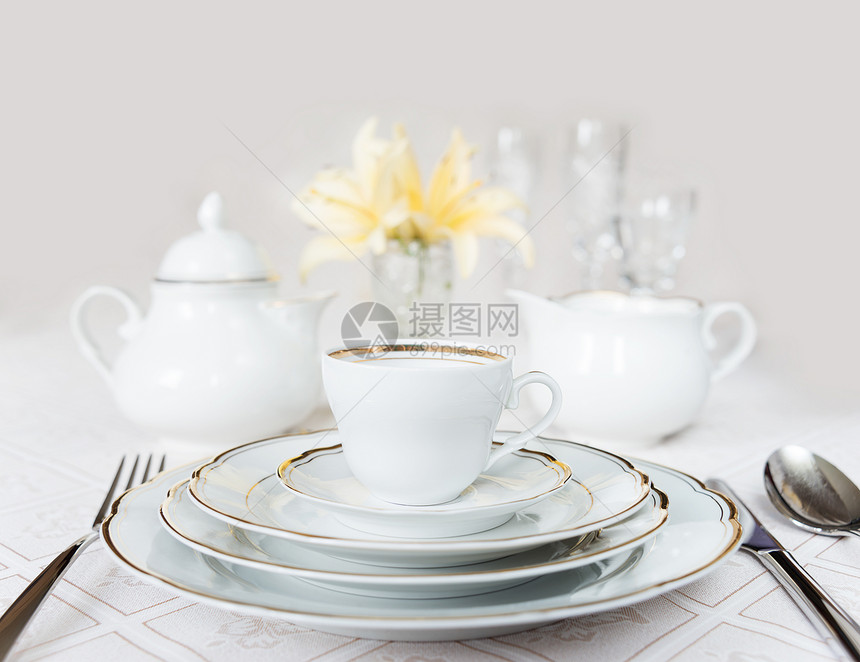 美的装饰桌上面有白色板晶杯水眼镜餐巾纸具和豪华桌布上的百花图片
