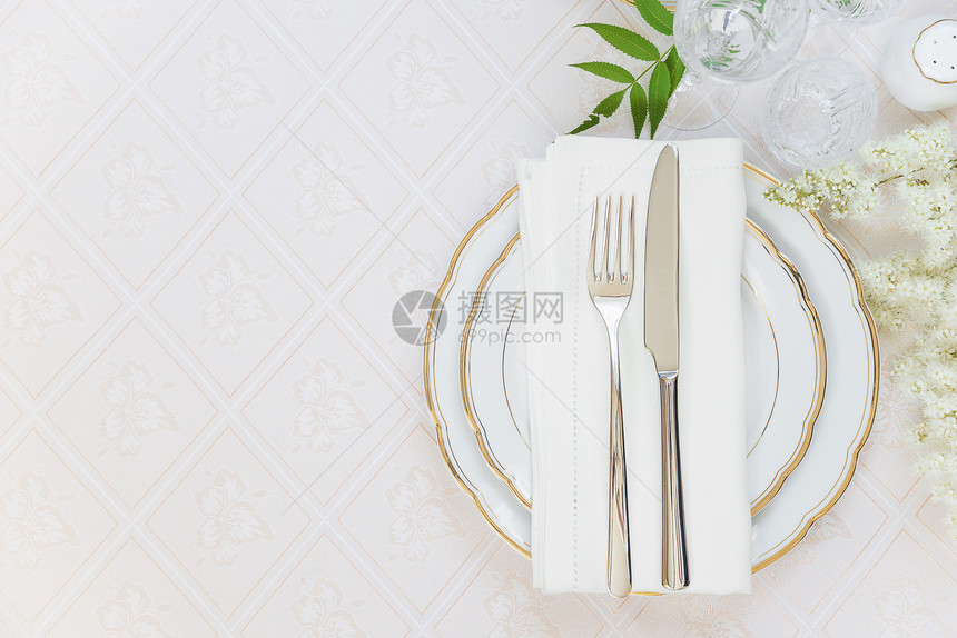 美的装饰桌顶上面有白色板晶杯水眼镜面巾餐具和白花在豪华桌布上有文字空间图片