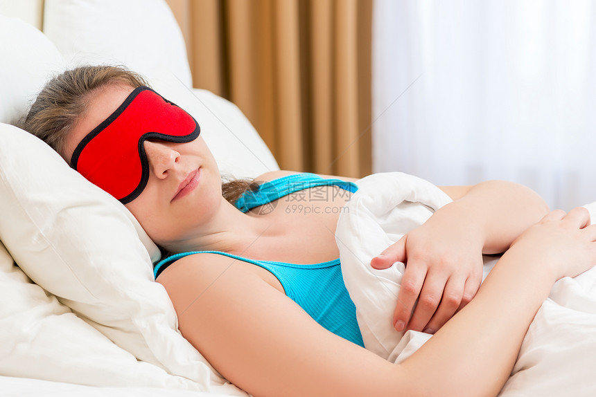 戴眼罩睡在毯子下的妇女图片