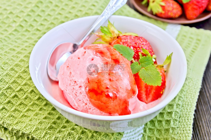 白碗中的草莓糖浆和在木板背景上的绿餐巾纸勺子草莓冰淇淋图片