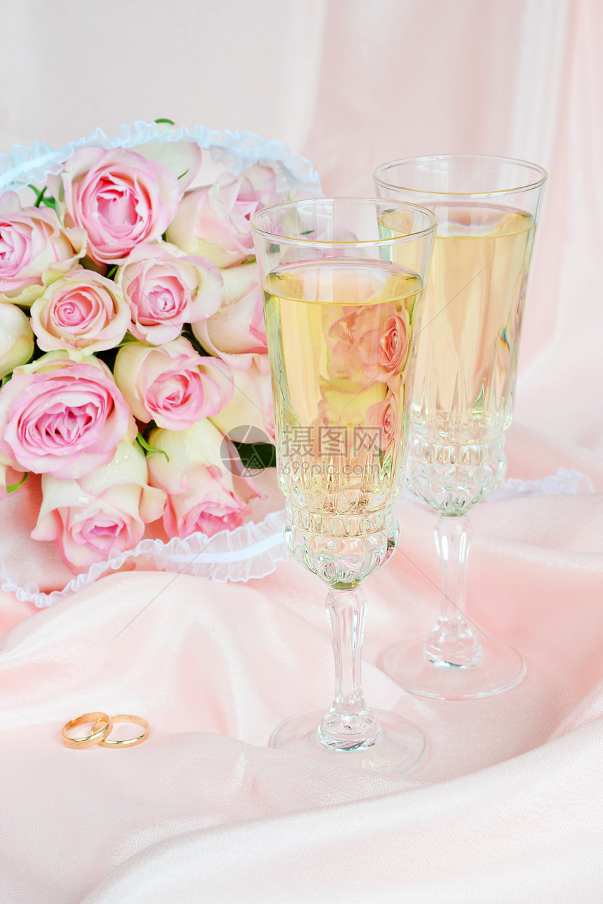 粉红玫瑰结婚戒指和两杯白葡萄酒的花束结婚戒指和两杯白葡萄酒图片