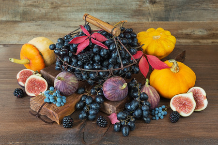 木藤古老的金属篮子中黑葡萄木柄和成熟的无花果红草莓橘子南瓜和黑莓木本底有秋叶背景