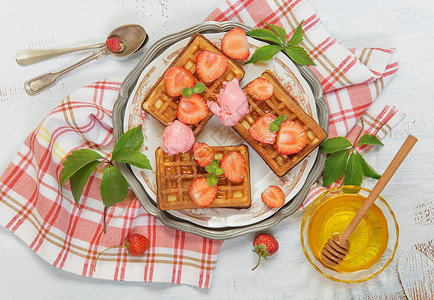 甜华夫饼鲜草莓蜂蜜和冰淇淋在美丽的盘子上站在一块压碎的餐巾纸上图片