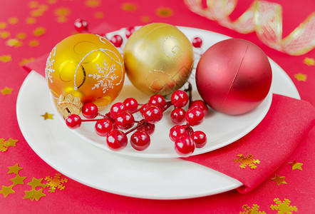 圣诞球和胡利浆果都放在白瓷板上红色桌布上图片
