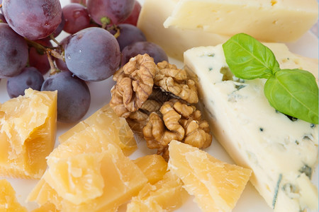 不同种类的奶酪胡桃红葡萄和叶背景图片