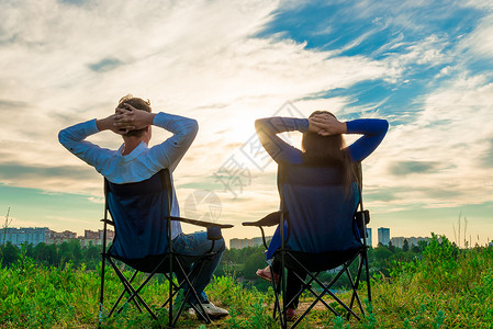 一对夫妇坐在椅子上仰慕城市的日出图片