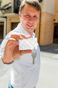 一个持干净卡片和房钥匙的男人垂直肖像图片
