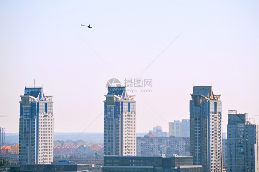 直升机在现代建筑物上空飞行图片