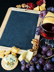 黑色背景的白白周围环绕着红酒各种奶酪核桃和葡萄图片