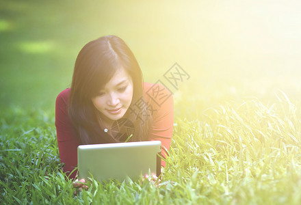 年轻的女人拿着平板在草坪上的唯美照片图片