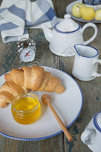 早餐包括一杯茶和带蜂蜜的羊角面包图片