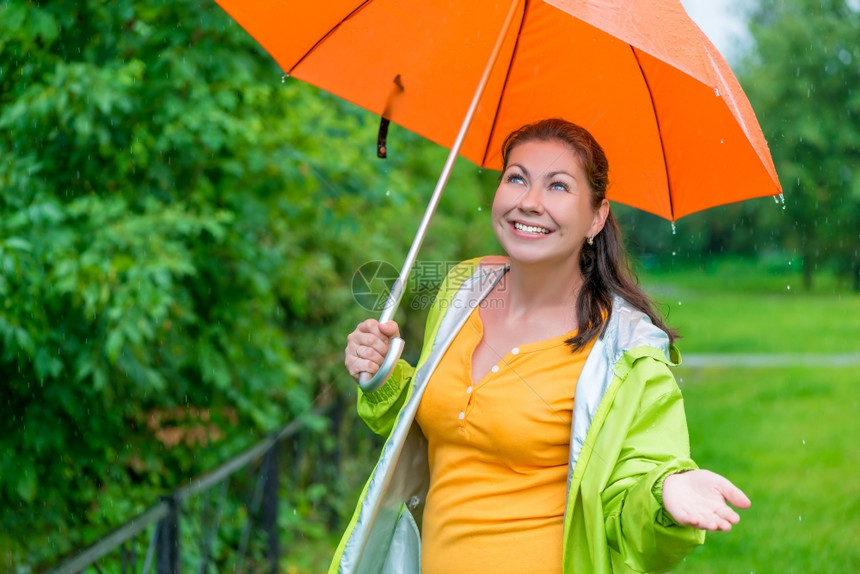 美丽的女孩带着明亮的橙色雨伞图片