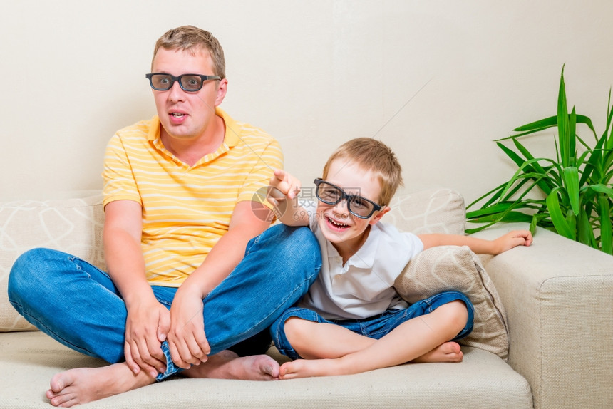 父子俩坐在沙发上戴着眼镜看电视图片