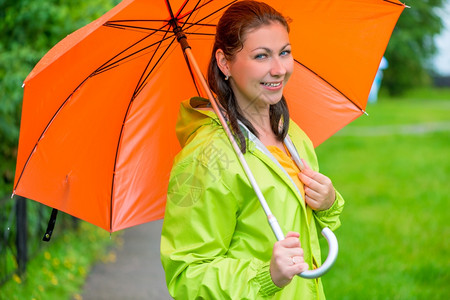 美丽的年轻黑发女带橙色雨伞的紧身衣图片