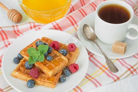 美味的早餐甜华芙饼草莓蓝和一杯咖啡放在餐巾纸上的图片