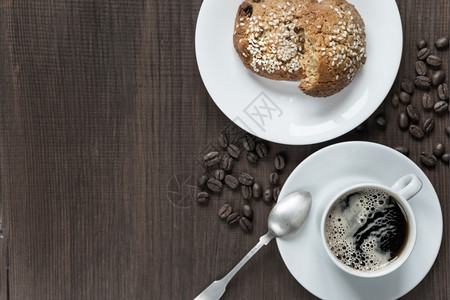 黑咖啡白瓷杯豆和燕麦饼干在黑木本底顶视面图片