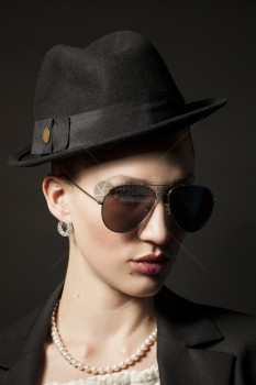 一个美丽的年轻模特肖像戴着黑帽子色背面戴墨镜的黑帽子图片