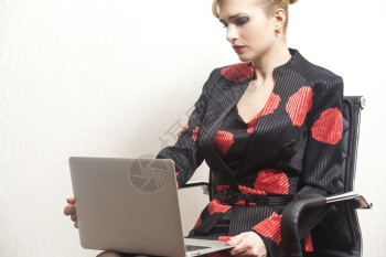 坐在椅子上并用笔记本在办公室工作的妇女图片