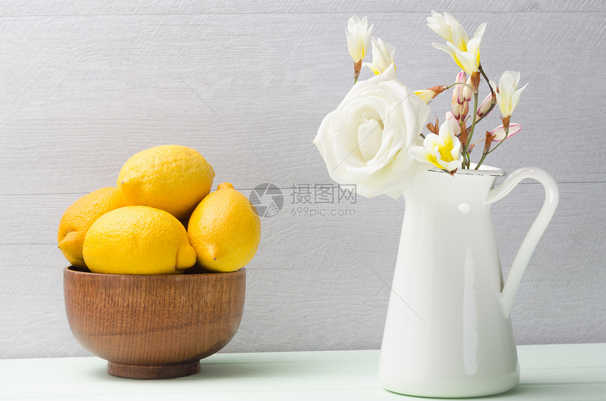 茶壶里装着柠檬和白花的木碗图片