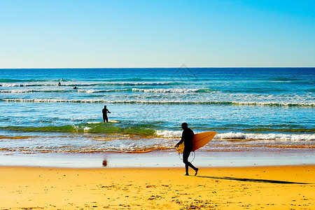 有冲浪板的者在阳光明媚的白天去海洋图片
