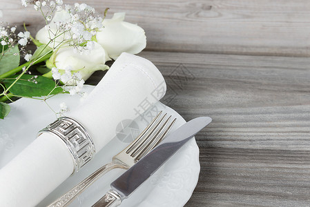 刀光白板餐巾具和白玫瑰花背景