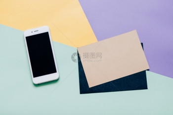 具有智能手机和空白信封的以现代多彩背景为主的具有智能手机和空白信封的工作间服务台图片