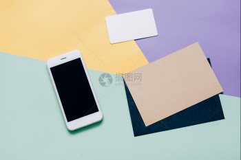 具有智能手机和空白信封及现代多彩背景名卡的有智能手机工作台图片