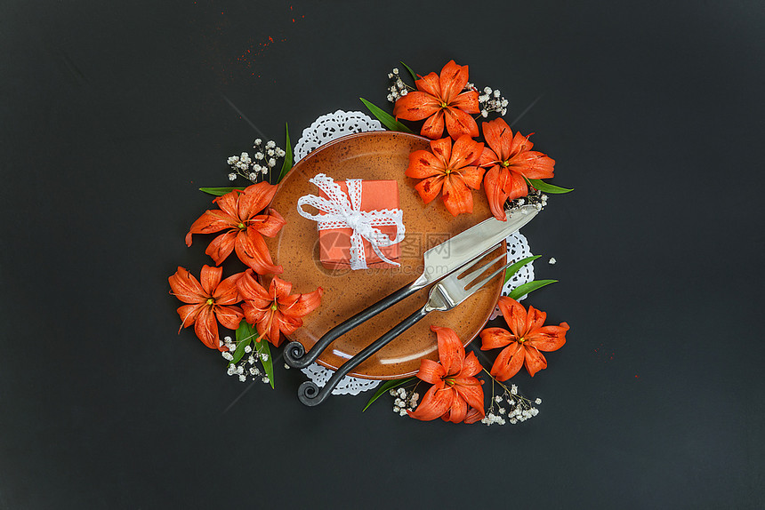 带有橙丽花和礼品盒的衣板装饰着橙色百丽花和礼品盒的衣板上面绑有白带丝和黑色桌上的独家伪造餐具顶楼平面图片