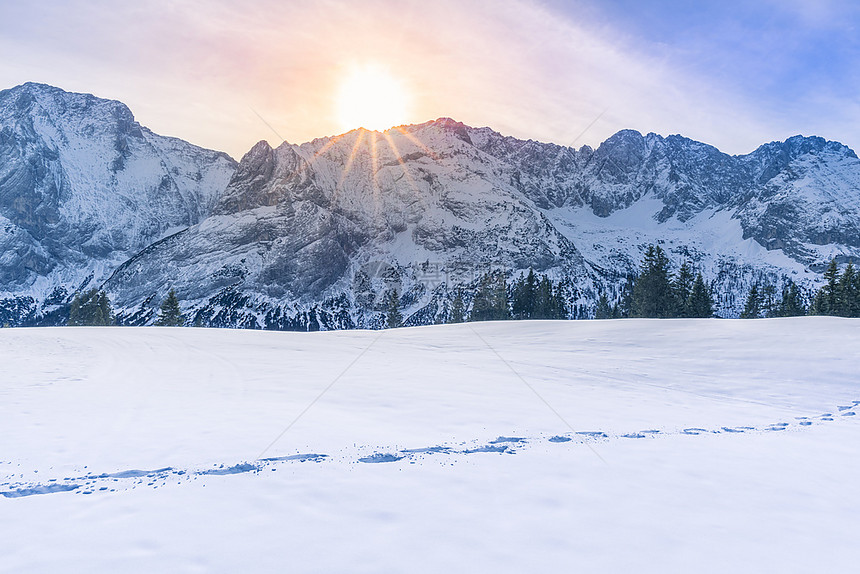 太阳照耀在被雪覆盖的山上图片