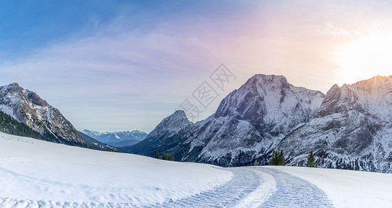 高山全景带雪路冬季风景由雪车铺设的一条路在12月的阳光明媚一天在奥斯特里亚高山上的雪层中留下痕迹背景图片