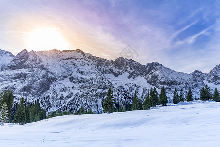 奥斯特西瓦尔德雪山峰美丽的冬季风景有奥斯特里亚山的岩石峰长青的林和被雪覆盖的牧场一切都被多彩的太阳暖和起来背景