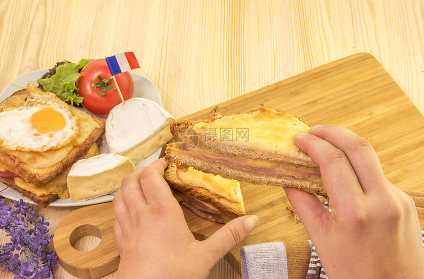 妇女手握三明治切片食物摄影片由美味的法国三明治croquemr制成背景中还有一张盘子和其他法国产品图片