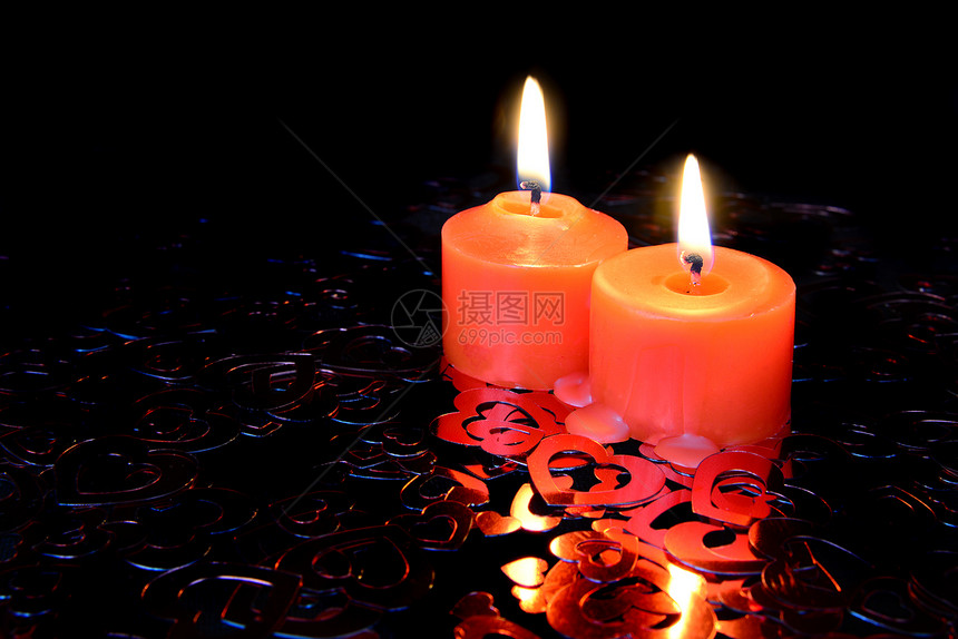 两根红蜡烛烧着在心形状的彩色面团黑暗背景上图片