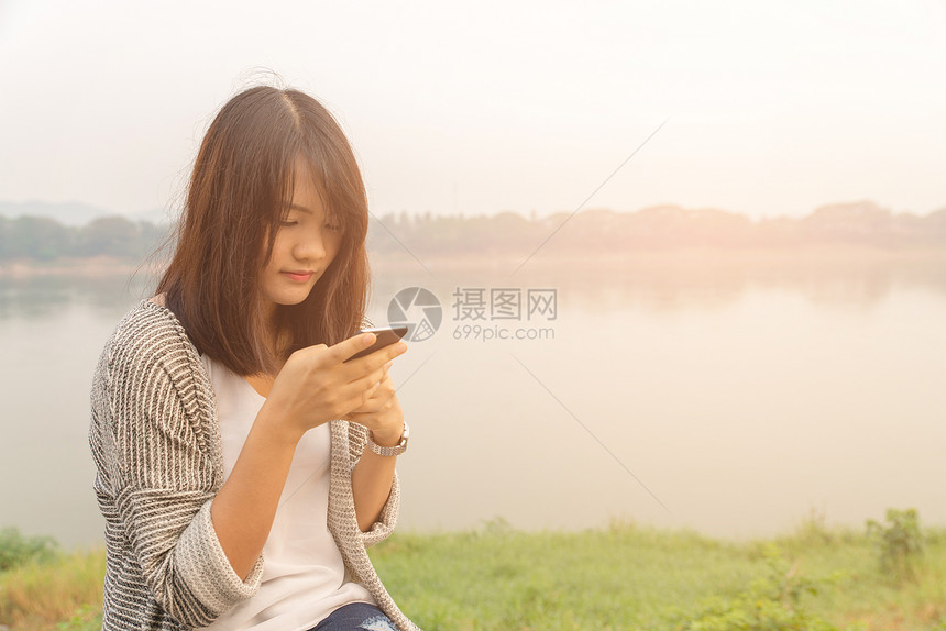 在公园玩手机的年轻女孩图片