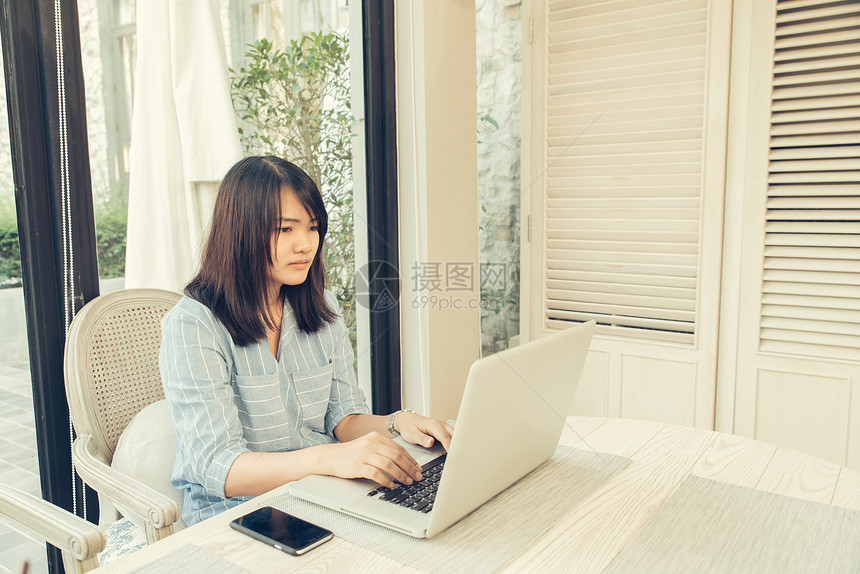 女人坐在咖啡店使用笔记本电脑上观看录像图片