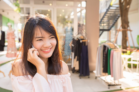 美丽的年轻黑发女打电话到店里图片