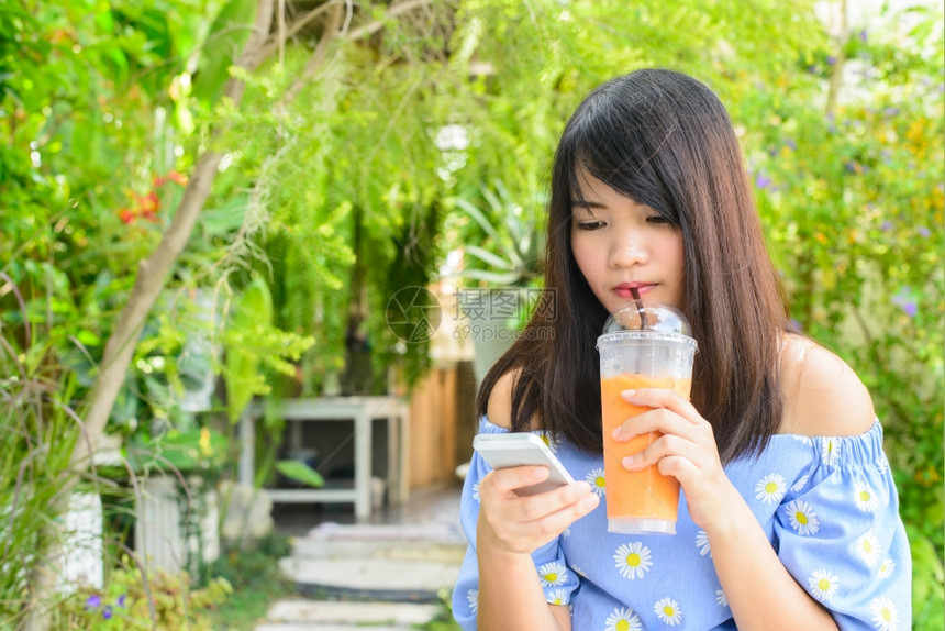 女孩一边喝果汁一边看手机图片