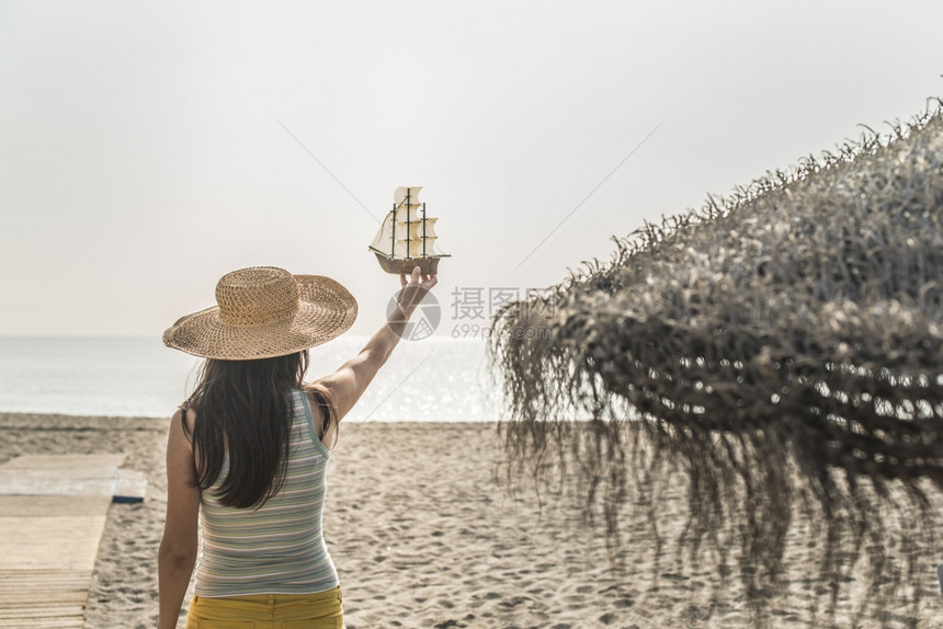 手上拿着帆船戴着帽子的女人图片