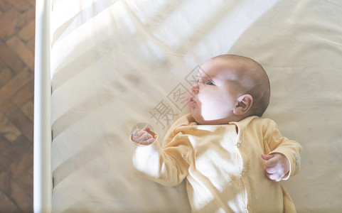 婴儿睡在白色的婴儿床上图片