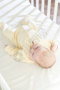 婴儿睡在白色的婴儿床上图片